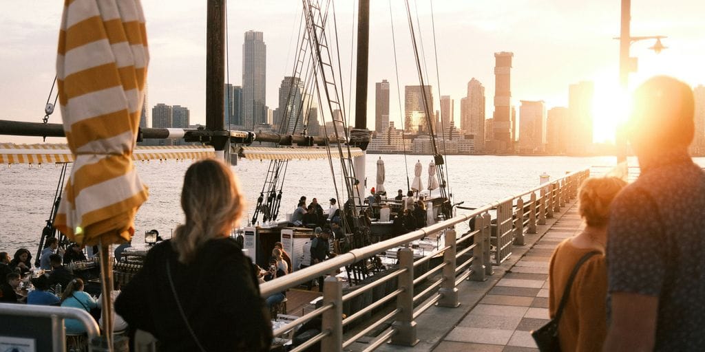 a group of people standing on a pier next to a body of water